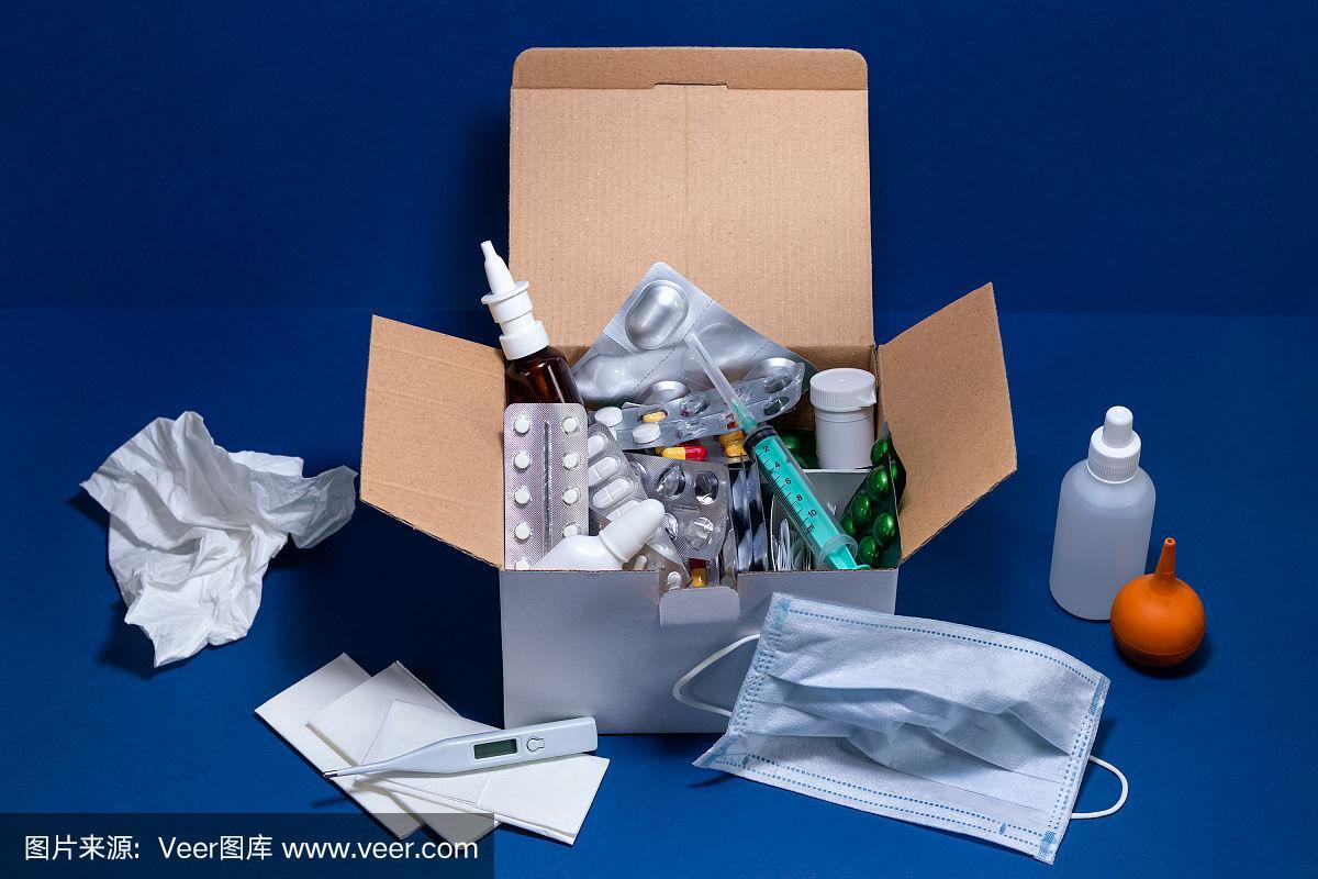 深蓝色背景的纸板箱,里面有医疗用品.泡罩包装的药片.感冒和流感季节